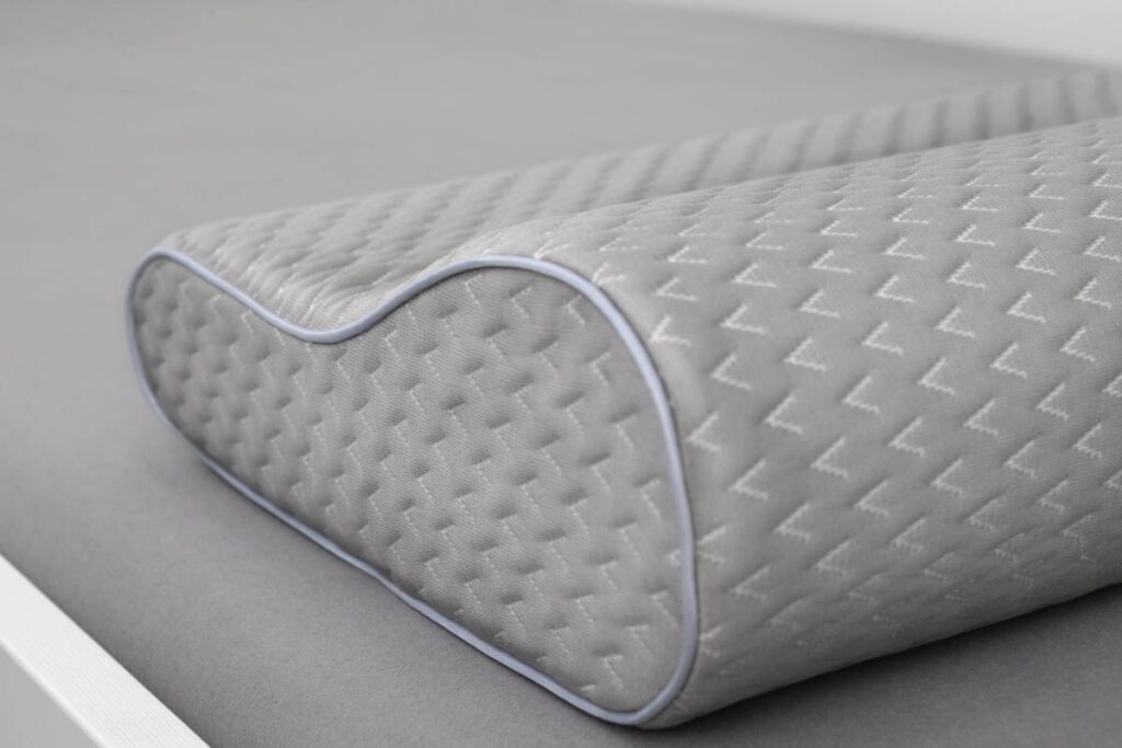 Gray orthopedic pillow made of memory foam on the bed. Slose-up shot