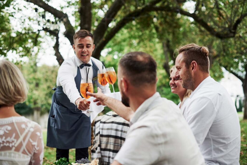 Here's your drink. Group of adult friends have a rest and conversation in the backyard of restaurant at dinner time