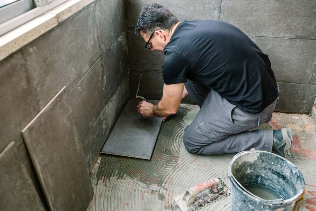 Workman laying a new tile floor on a terrace