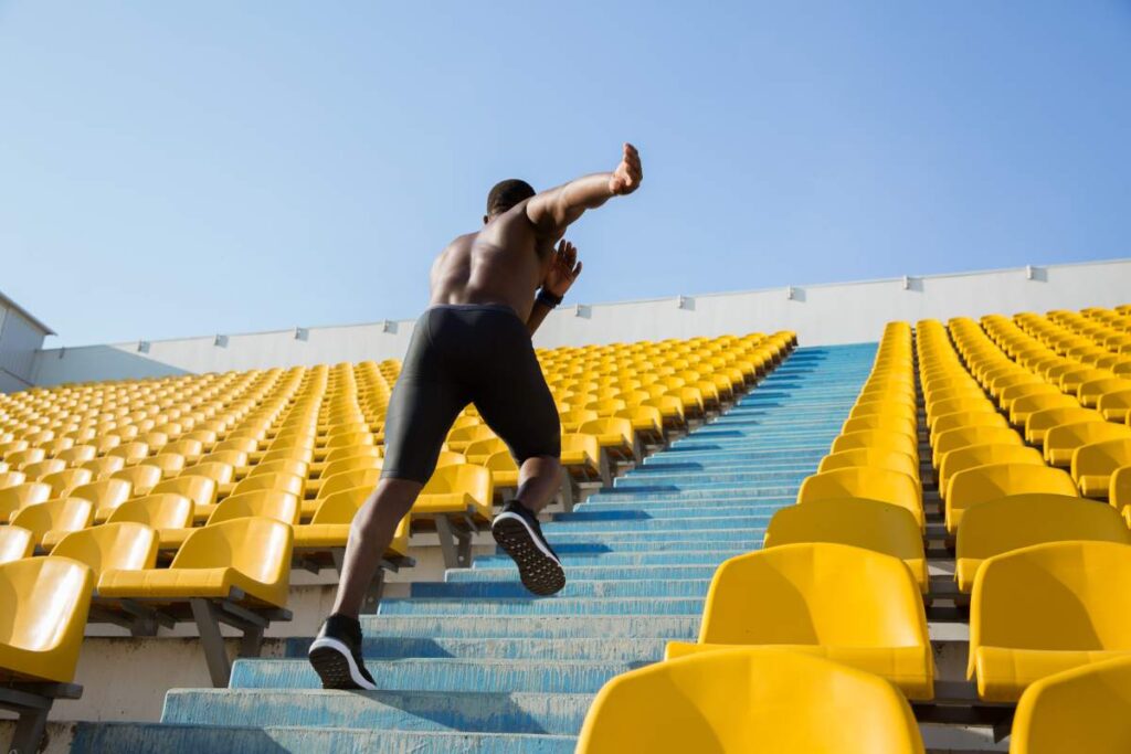 Active young african sportsman climbing up the stairs at the stadium