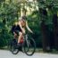 Sporty young woman and man on bicycles during weekend cycle ride in the nature. Wearing sports clothes and helmets. Traveling by high-performance sport bicycles. Sports lifestyle. Focus on a woman.