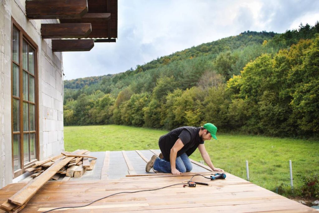 Handyman installing wooden flooring in patio, working with drilling machine