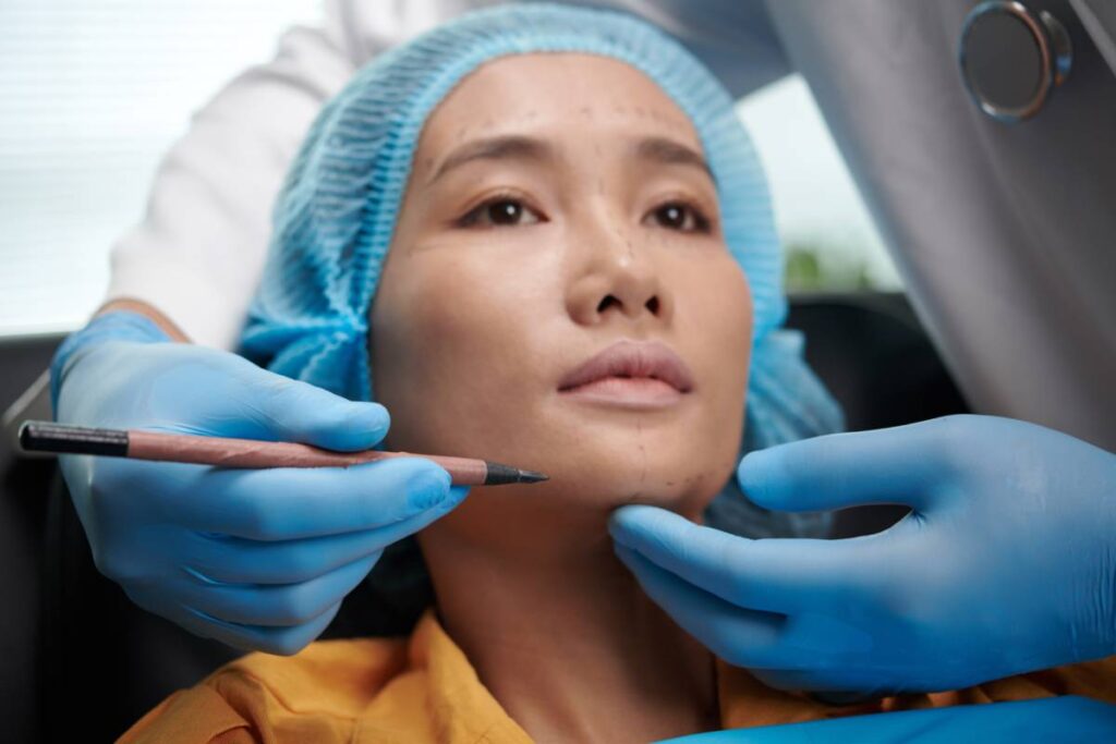 Doctor marking areas on face of patient before facelift surgery